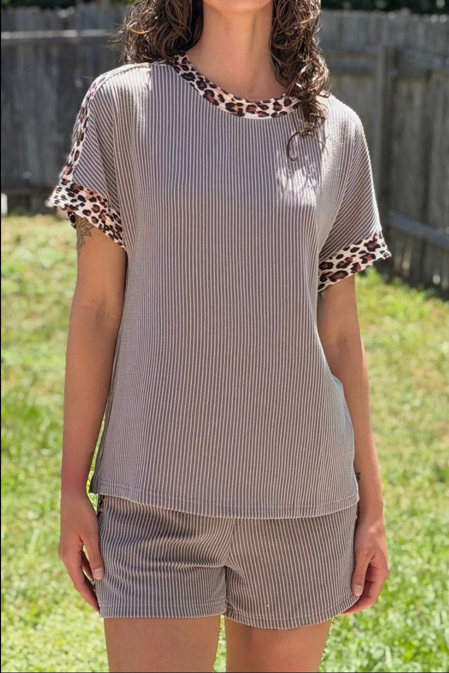 Person wearing a gray striped outfit with leopard print accents outdoors.