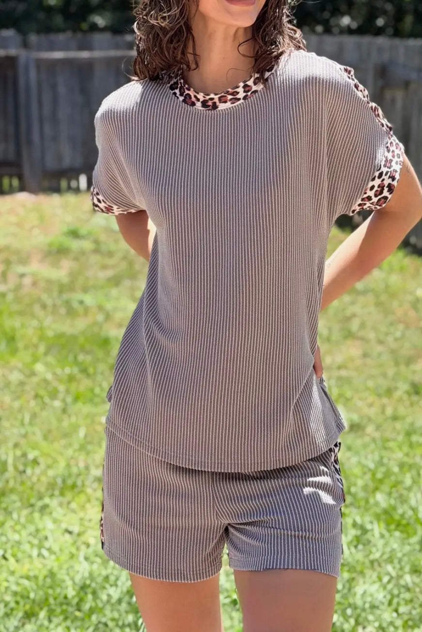 Woman wearing a striped shirt and shorts set with leopard print accents outdoors.