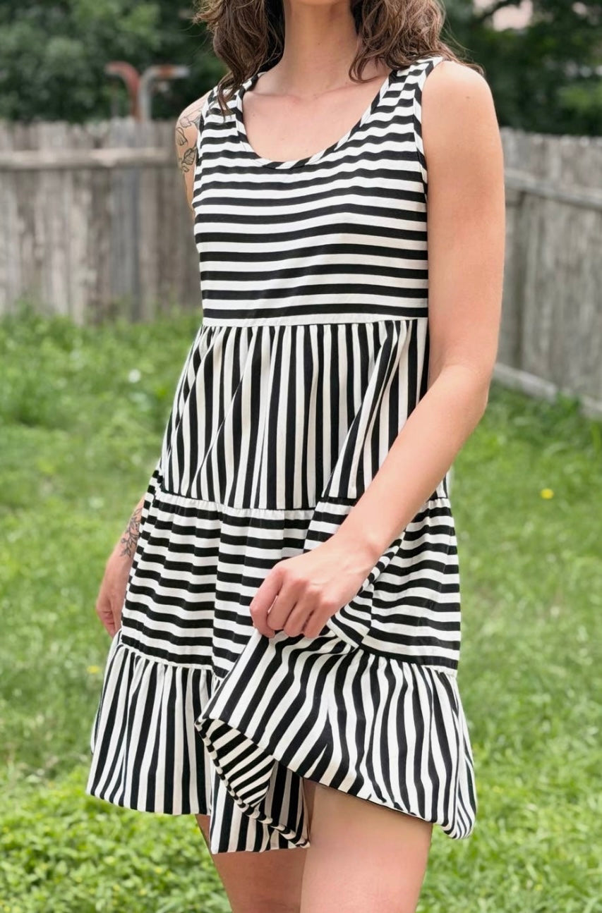 Person wearing a black and white striped dress standing in a grassy area.