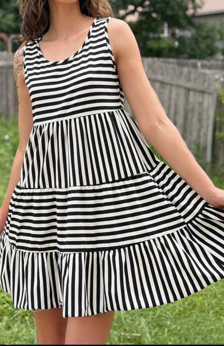Person wearing a black and white striped dress outdoors.