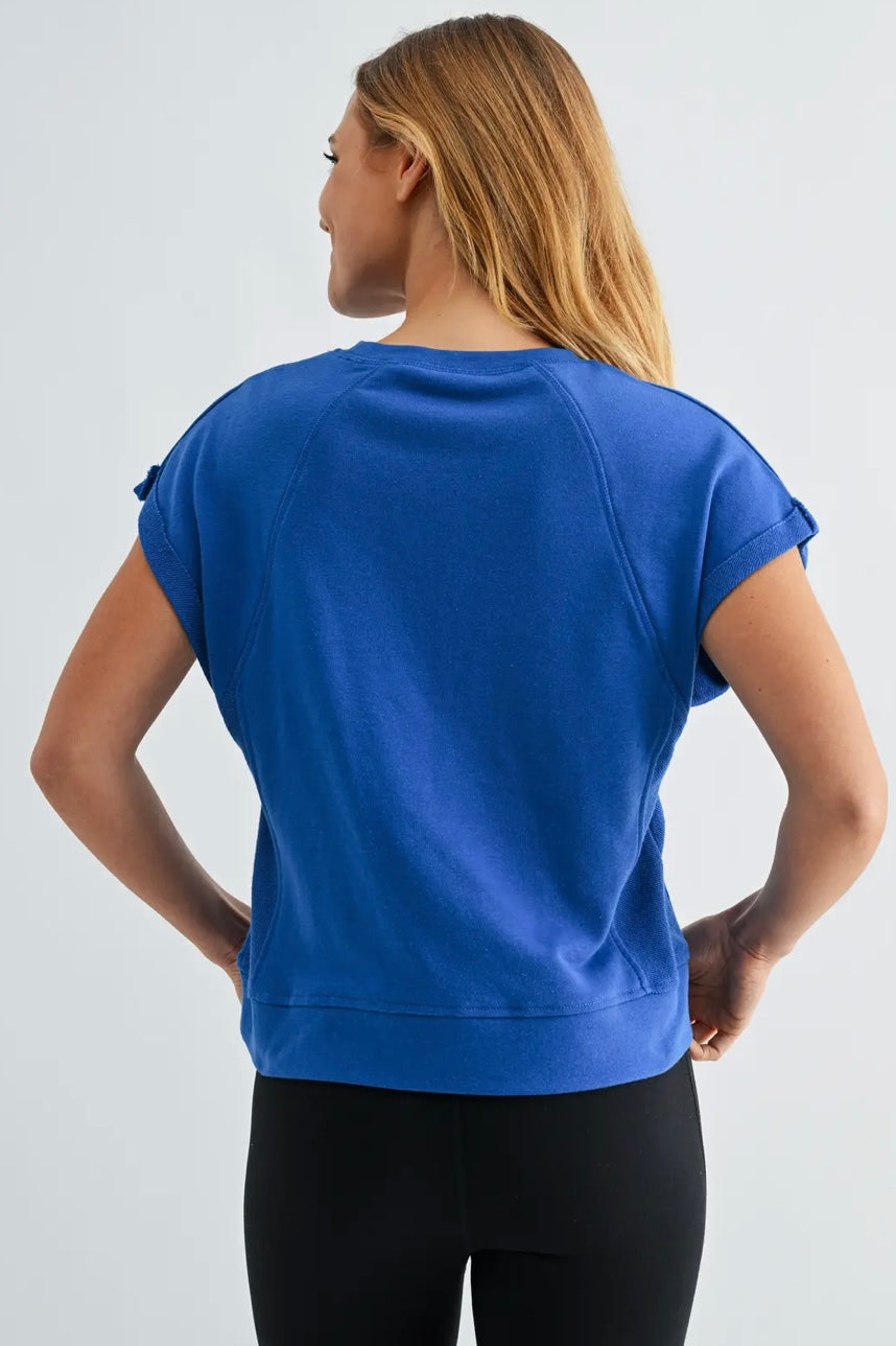 Person wearing a blue athletic top and black leggings on a light gray background