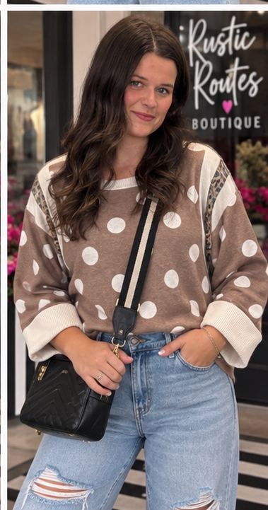 Front view of mocha oversized ivory polka dot top featuring leopard shoulder accents, a ribbed neckline and wide ivory cuffs with blue jeans.