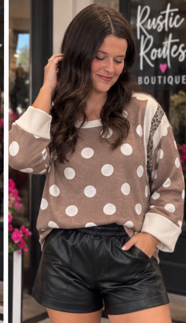 Mocha and ivory polka dot boutique top with relaxed sleeves and leopard print accents styled with black faux leather shorts.