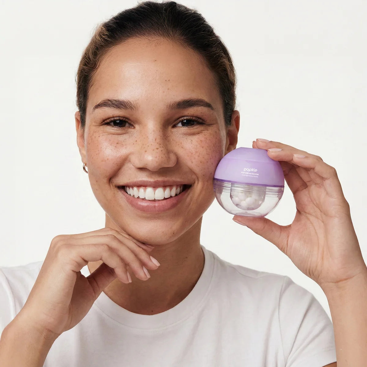 Woman holding a purple skincare device against a white background