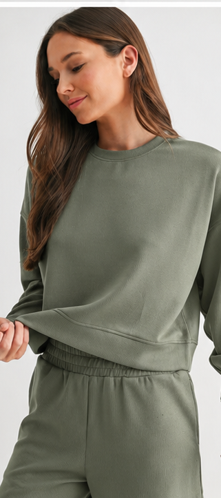 Woman wearing elder green ribbed cropped sweatshirt with matching lounge shorts