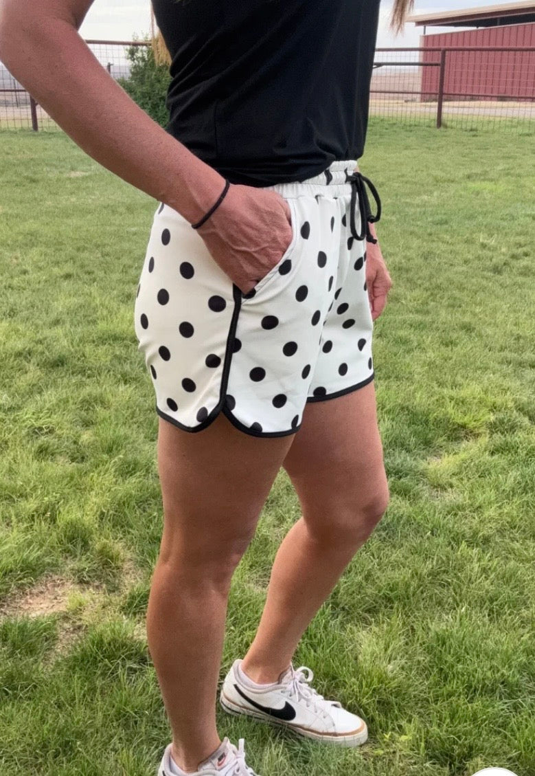 Person wearing black and white polka dot shorts on a grassy field
