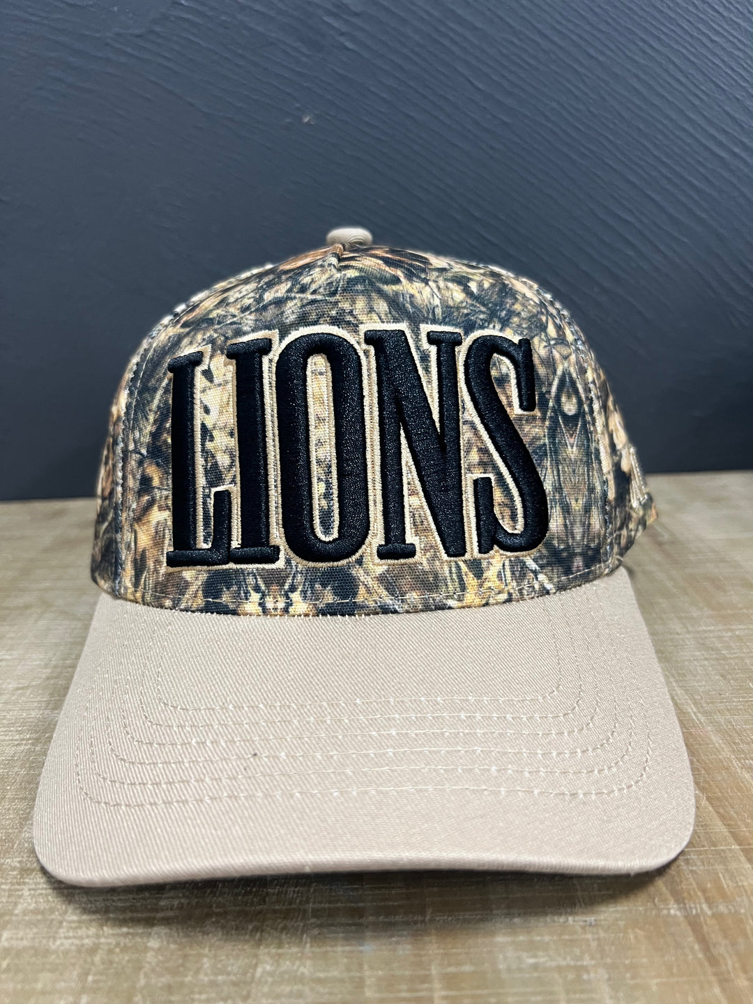 Camo Lions mascot hat with black puff embroidery, light brown outline, and matching light brown brim.