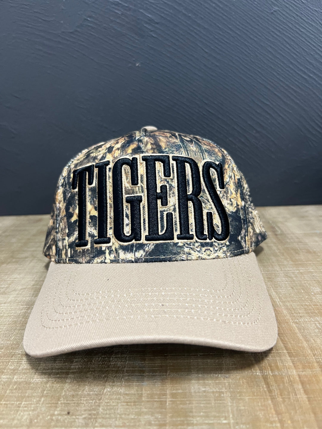 Camo Tigers mascot hat with raised black lettering, light brown outline, and light brown brim.