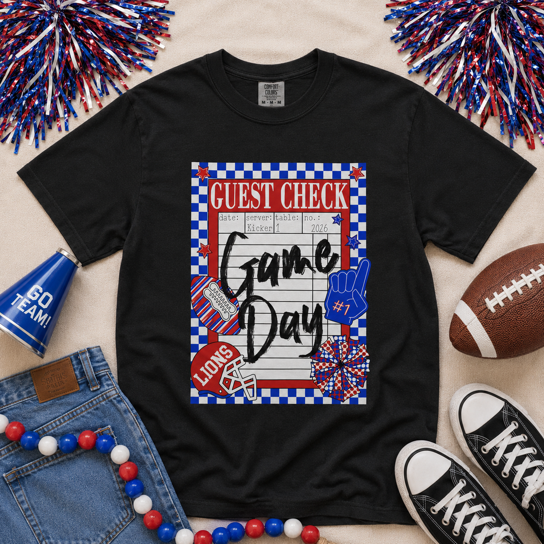 Black Comfort Colors Lions game day guest check graphic tee featuring red and royal blue school colors, checkerboard border, football helmet, foam finger, and custom Chandler Lions spirit design.