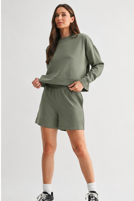 Woman wearing a green sweatshirt and shorts set on a white background