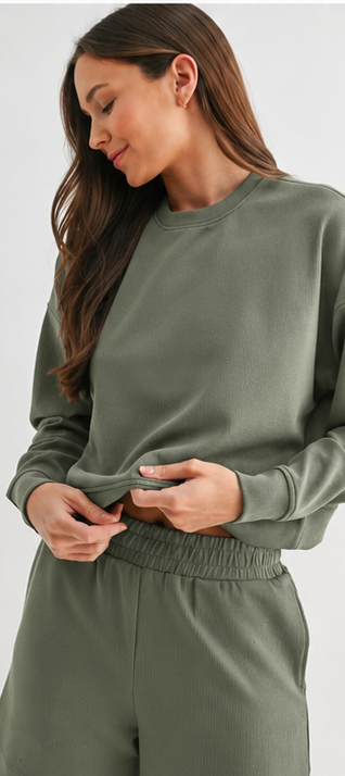 Woman wearing a green sweatshirt and pants set on a white background