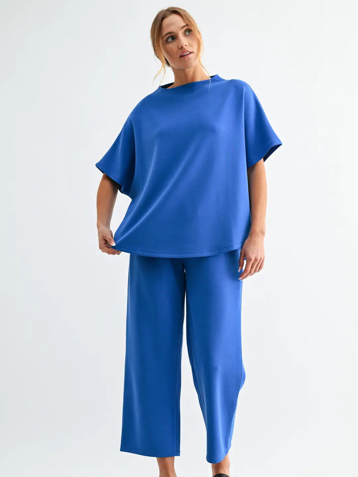 Model wearing the Mono B Laguna Casual Comfort Set with relaxed short sleeve top and cropped wide-leg pants in bright blue modal blend fabric.