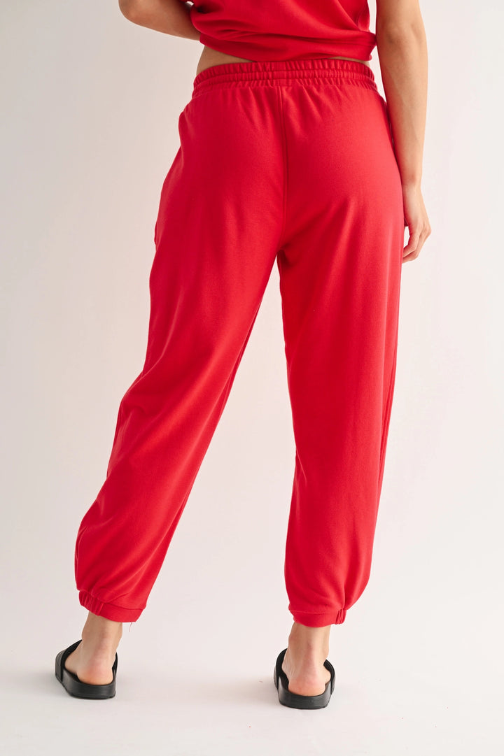 Back view of red Mono B joggers with elastic waistband and tapered leg