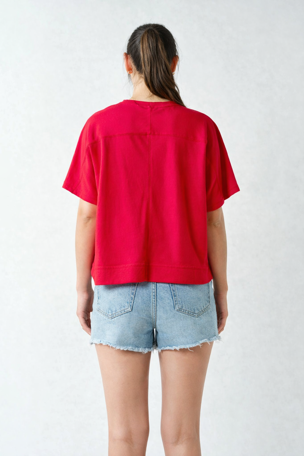 Back view of red Mono B French terry tee styled with light denim shorts