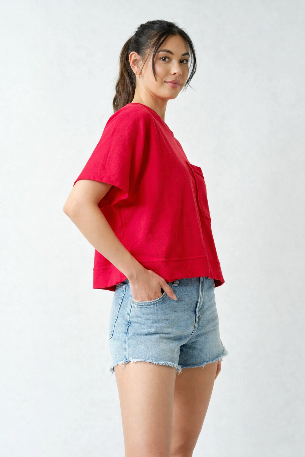 Side view of red Mono B pocket tee paired with light wash denim shorts casual outfit