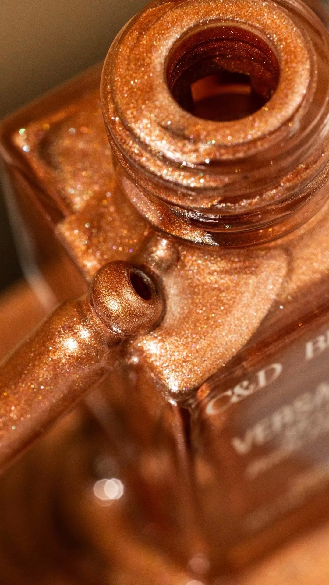 Detailed close-up of VersaGlow All Over Body Highlight revealing its sparkling bronze body shimmer formula.